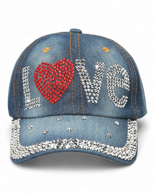 Blue denim baseball cap with rhinestone "LOVE" design, red heart detail, and rhinestone trim on the brim.
