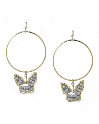 A pair of gold-tone hoop earrings with butterfly charms adorned with intricate beadwork, offering an elegant and whimsical accessory.