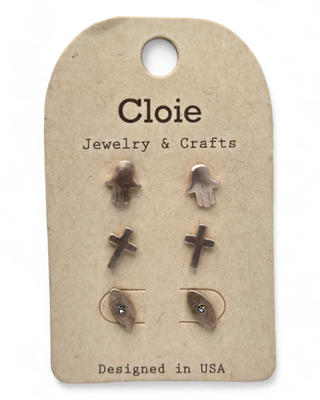 A set of stud earrings displayed on a card, including designs of hands, crosses, and evil eye