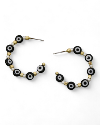 Gold-tone hoop earrings adorned with black and white evil eye beads and small golden spheres