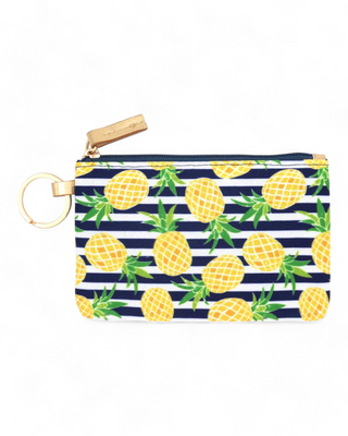 extile ID holder decorated with a vibrant pineapple pattern on navy stripes, equipped with a gold ring for keys and a clear front pocket for ID display.