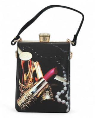 Box handbag with a print of red lipstick, gold makeup tubes, and pearl necklace, finished with a black handle and gold clasp.