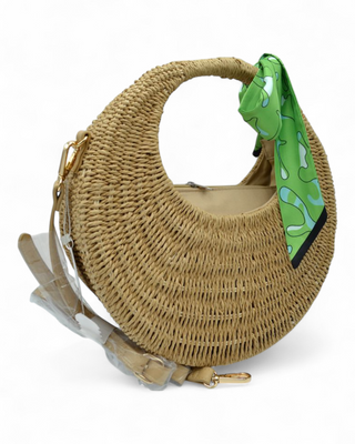 Round woven raffia handbag with a colorful scarf tied to the handle and detachable strap.