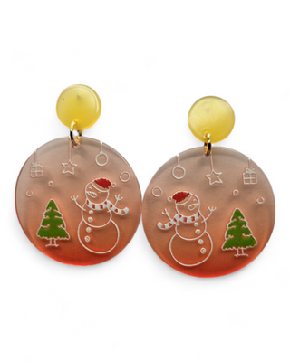Round acrylic earrings featuring an etched design of a snowman wearing a Santa hat and a Christmas tree. The earrings have yellow circular tops with holiday-themed decorations engraved on the main disc.