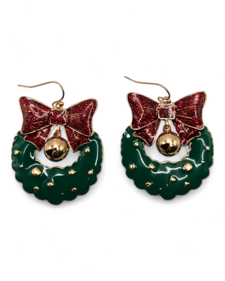 A pair of festive holiday wreath earrings with red glitter bows and golden bells. The green wreath design is embellished with gold accents, and the earrings have a shiny, metallic finish,